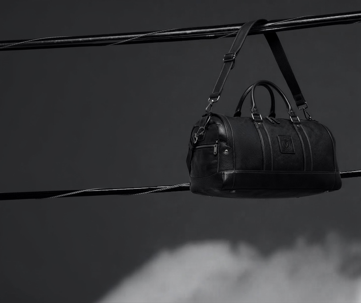 DABLZ 01 black duffel suspended in a dark studio